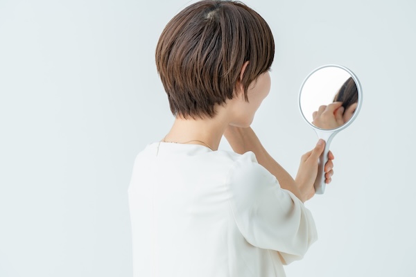 鏡で髪の状態を見てチェックする女性